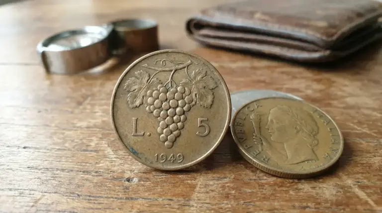 Moneta italiana da 5 lire del 1949 con grappolo d'uva su tavolo di legno